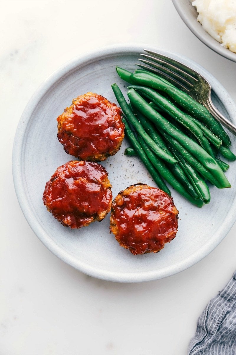 Delicious Mini Turkey Meatloaves with Green Beans Ready-to-eat mini turkey meatloaves next to green beans.