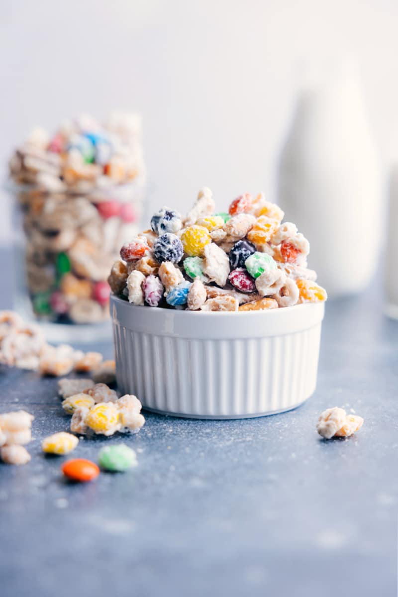 The BEST White Chocolate Chex Mix -- cereal, pretzels, peanuts, and M&M's, all coated in white chocolate. Recipe via ChelseasMessyApron #dessert #best #quick #easy #simple #m&ms #familyfriendly #kidfriendly #pretzels #cereal #whitechocolate #snackmix Image of a bowl of white chocolate snack mix