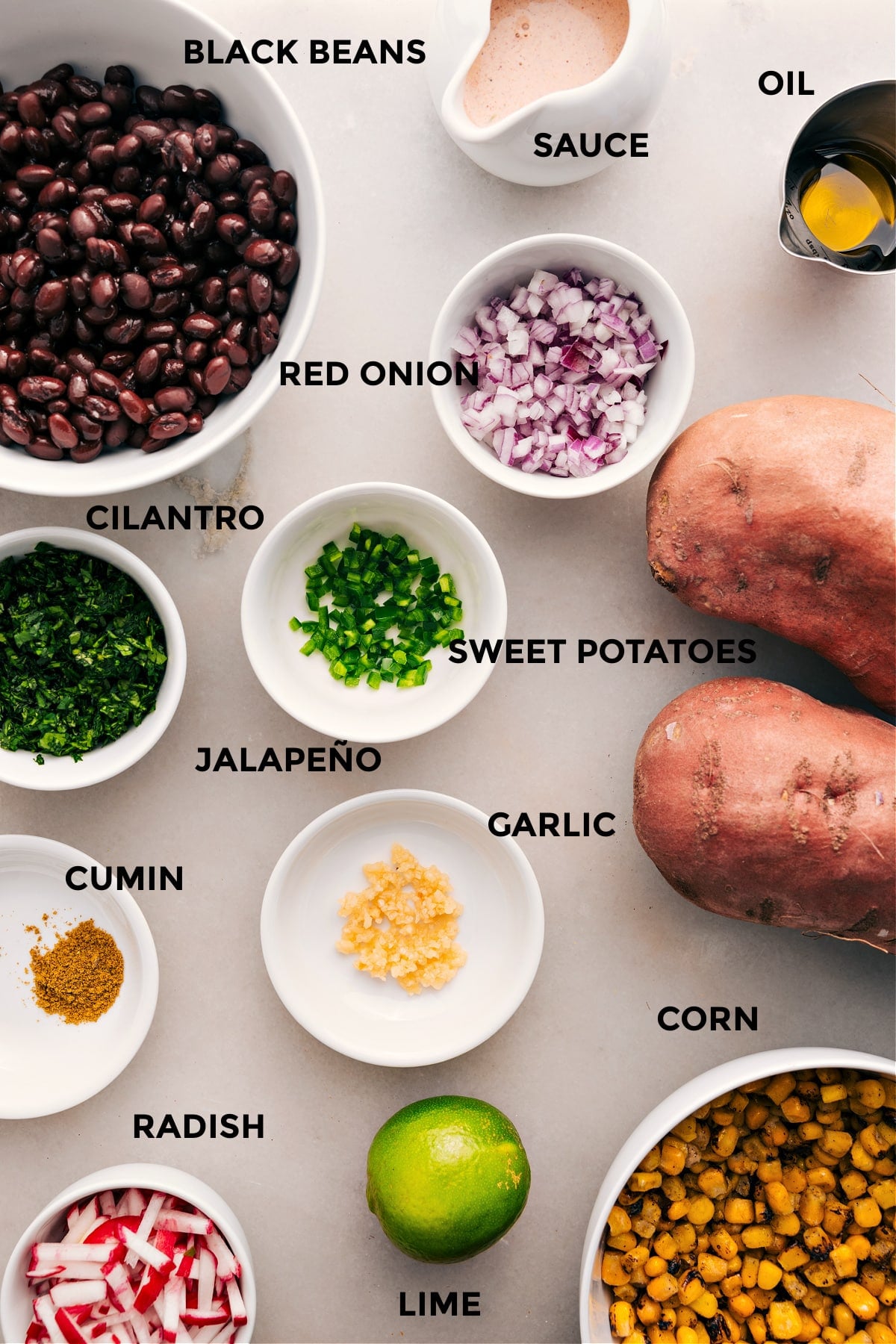 Ingredients In Stuffed Sweet Potatoes This recipe organizes all the ingredients for easy assembly: black beans, sauce, oil, onion, cilantro, sweet potatoes, corn, garlic, radishes, and lime.