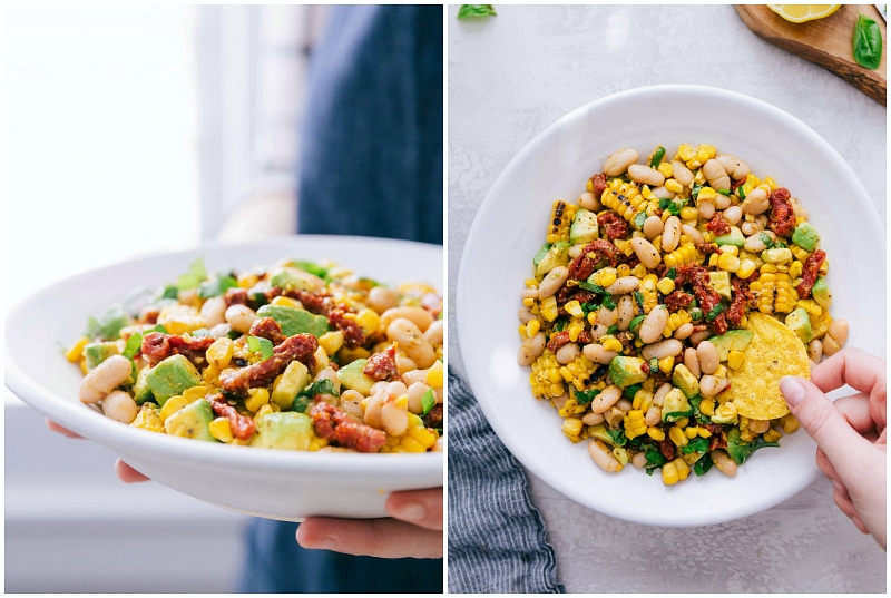 This White Bean Salsa with creamy avocado, crisp corn, savory sun-dried tomatoes, fresh lemon, and sweet basil is our latest obsession! It's perfect over grilled Pesto Chicken! Recipe via Chelseasmessyapron #healthy #keto #whole #protein #whole30 #best #avocado #corn #sundriedtomatoes #clean #cleaneating #whitebean #salsa White Bean Salsa being served and a chip being dipped into it