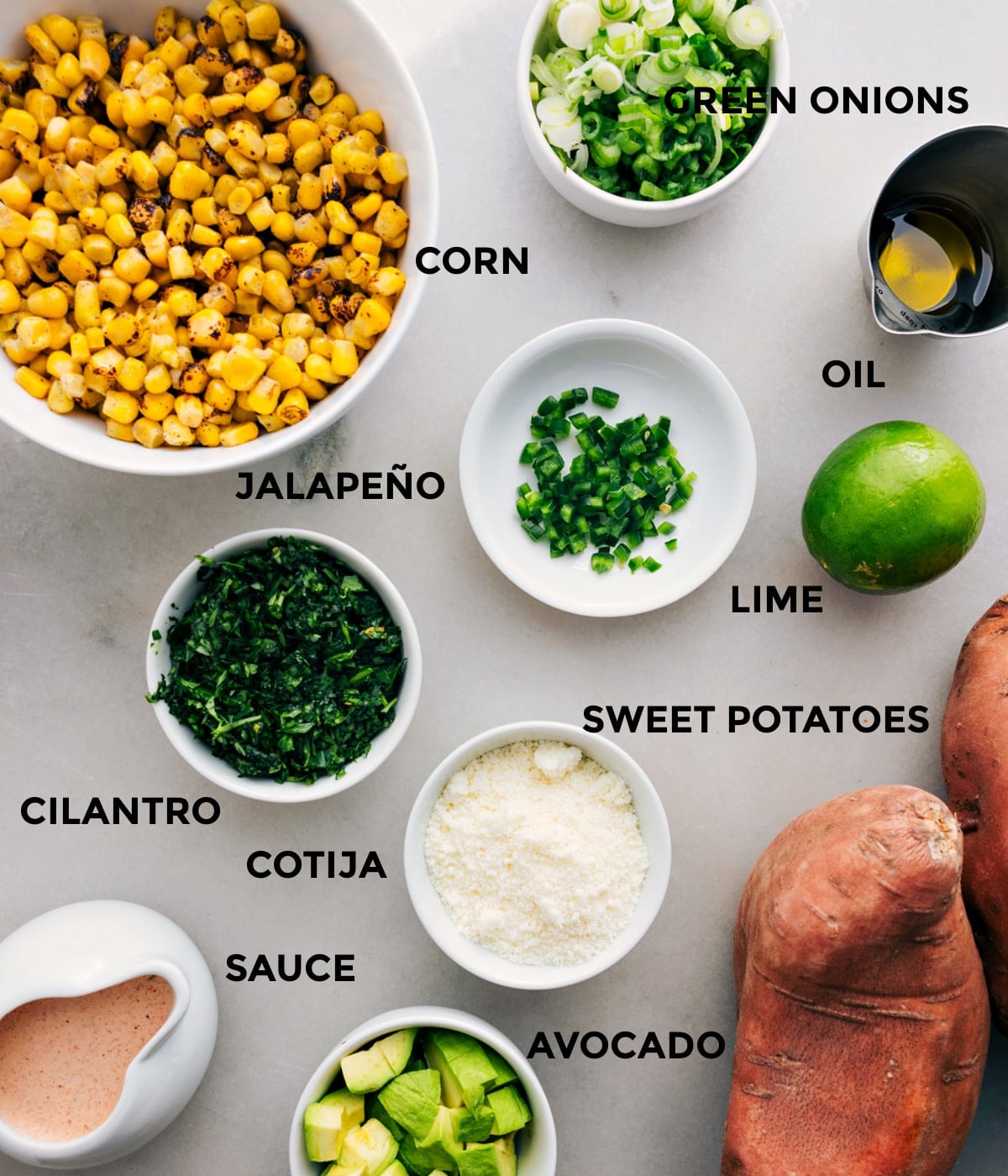 Ingredients In Loaded Sweet Potatoes This recipe has everything prepped for easy assembly—corn, green onions, oil, lime, jalapeño, veggies, cotija, and sauce.