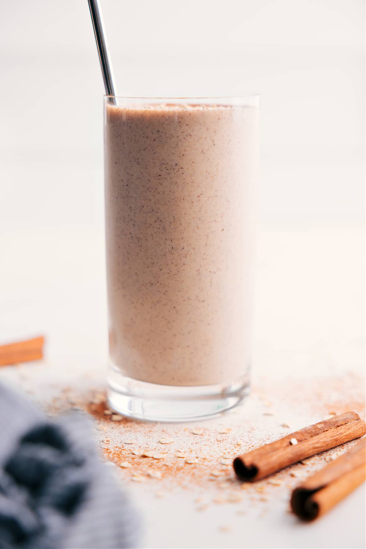 Creamy oatmeal smoothie in a glass with a straw.