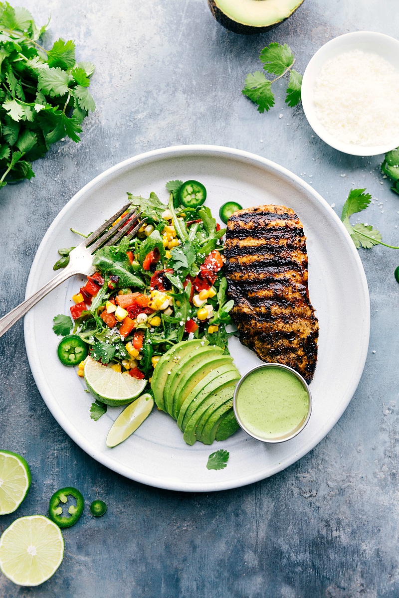 Delicious Peruvian Chicken Plate with Fresh Salad and Avocado A plate filled with Peruvian chicken, a fresh salad, creamy avocado slices, and a vibrant green sauce, creating a healthy and delicious meal.