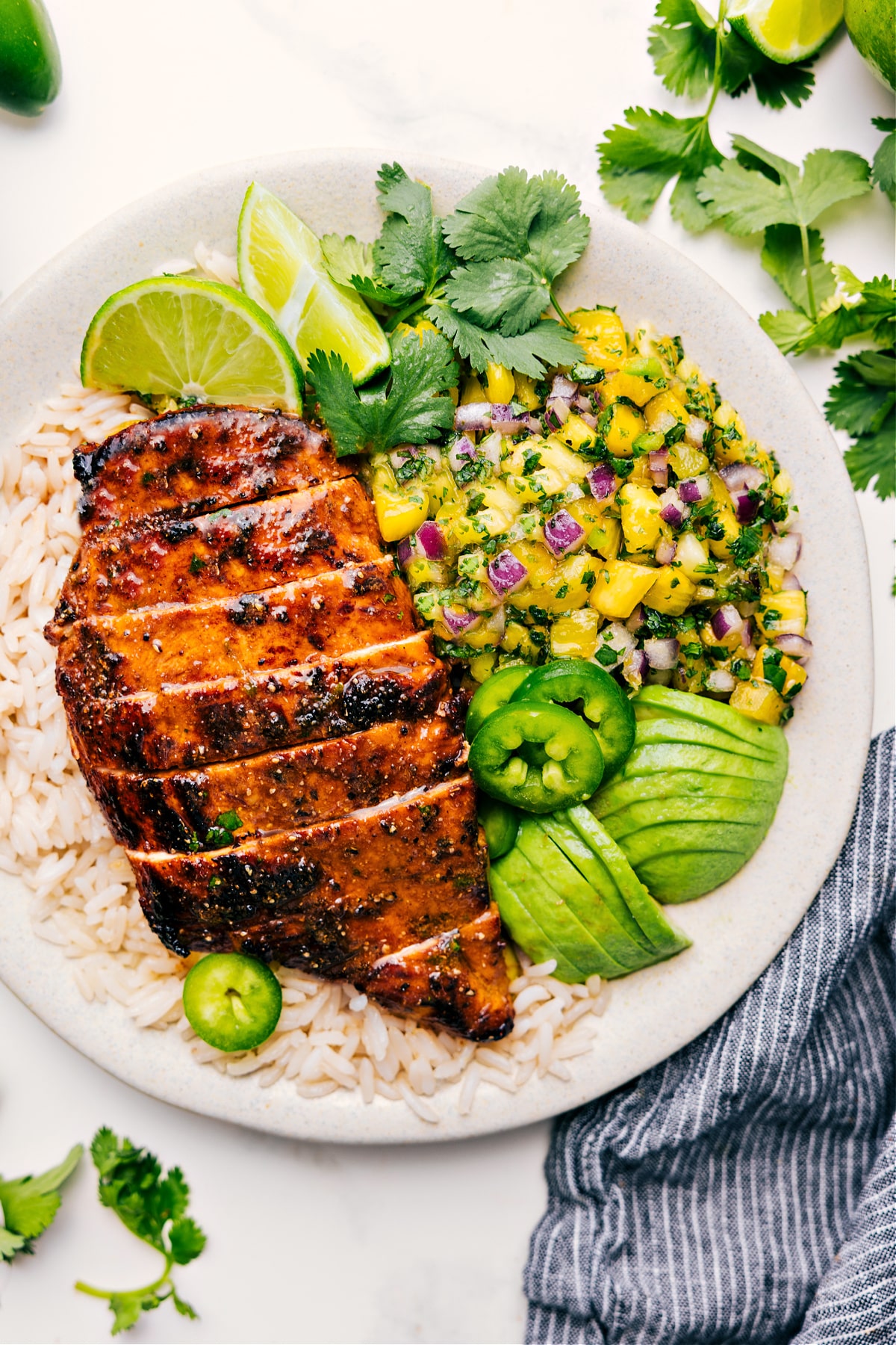 Pineapple Chicken served over rice with fresh pineapple salsa, avocado, and jalapeño on the side.
