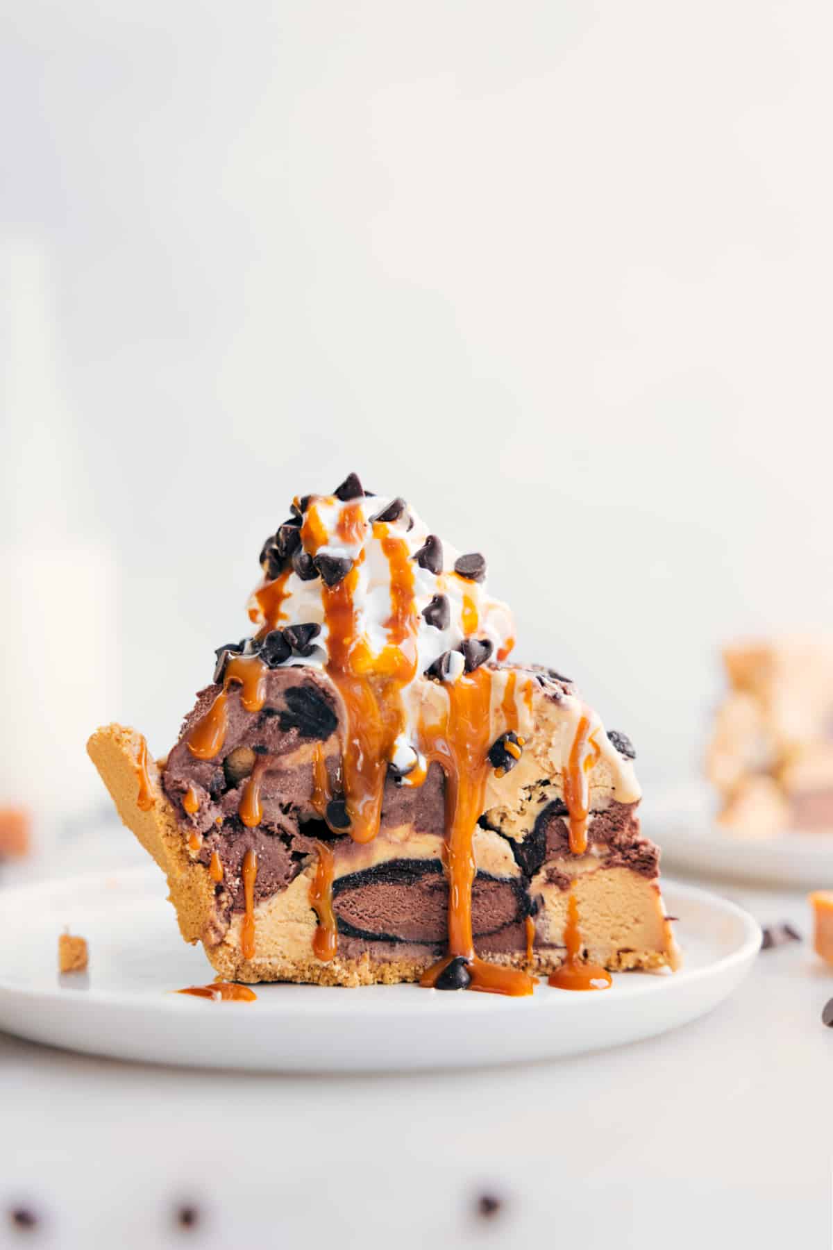 The Best Ice Cream Pie Recipe That Takes Minutes To Prepare Slice of Ice Cream Pie with whipped cream, drizzle of caramel, and chocolate chips on top.