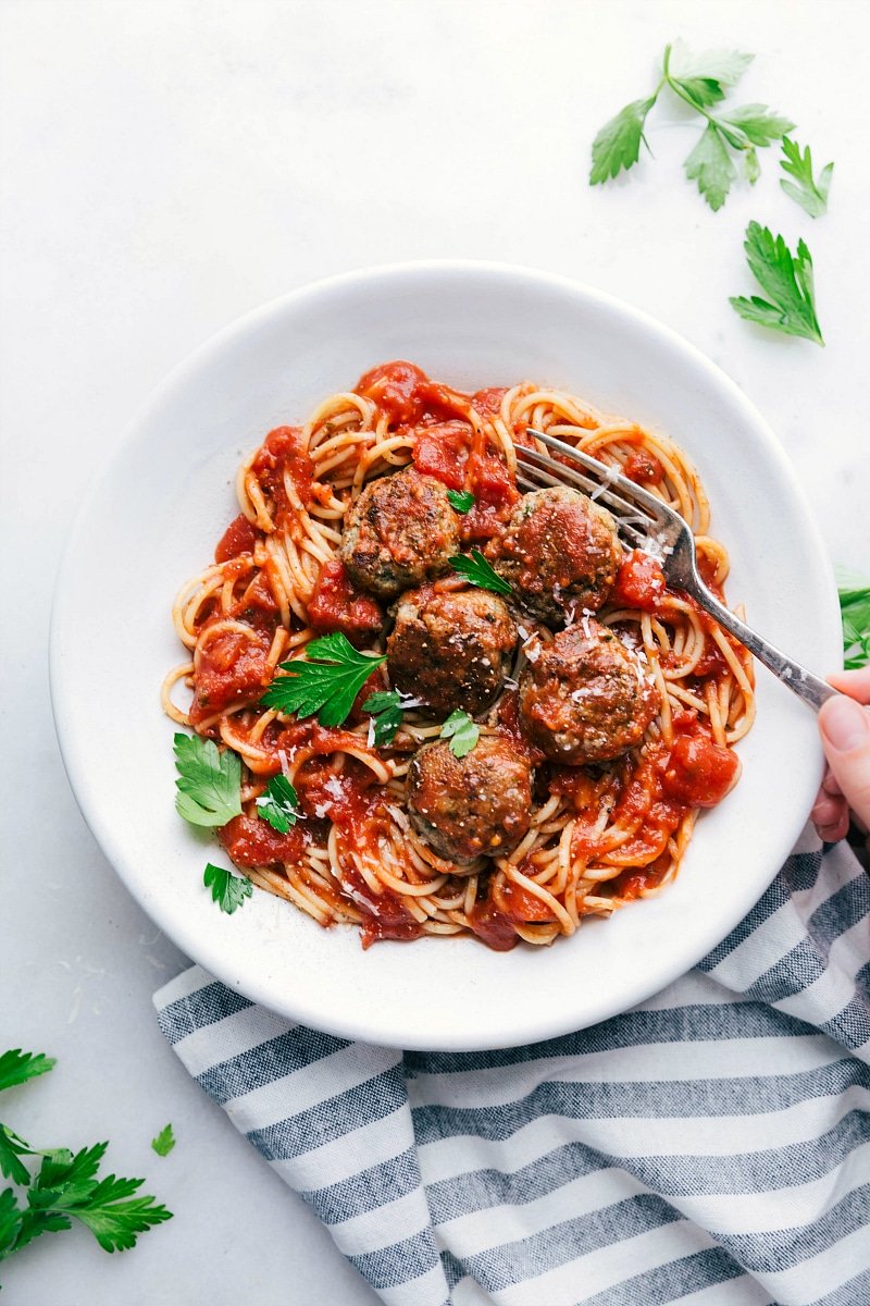 Finished Turkey Meatballs Over Spaghetti with Marinara Sauce and Fresh Herbs, Ready to Be Enjoyed A bowl of finished turkey meatballs nestled over a bed of spaghetti, generously coated with marinara sauce and topped with fresh herbs, creating a hearty and inviting meal ready to be enjoyed.