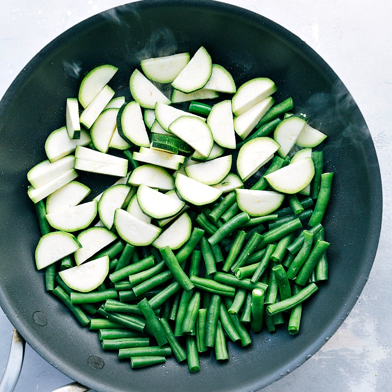 Pre-Sauté Stage: Fresh Zucchini and Green Beans in a Skillet Uncooked zucchini and green beans in a skillet, ready for sautéing.