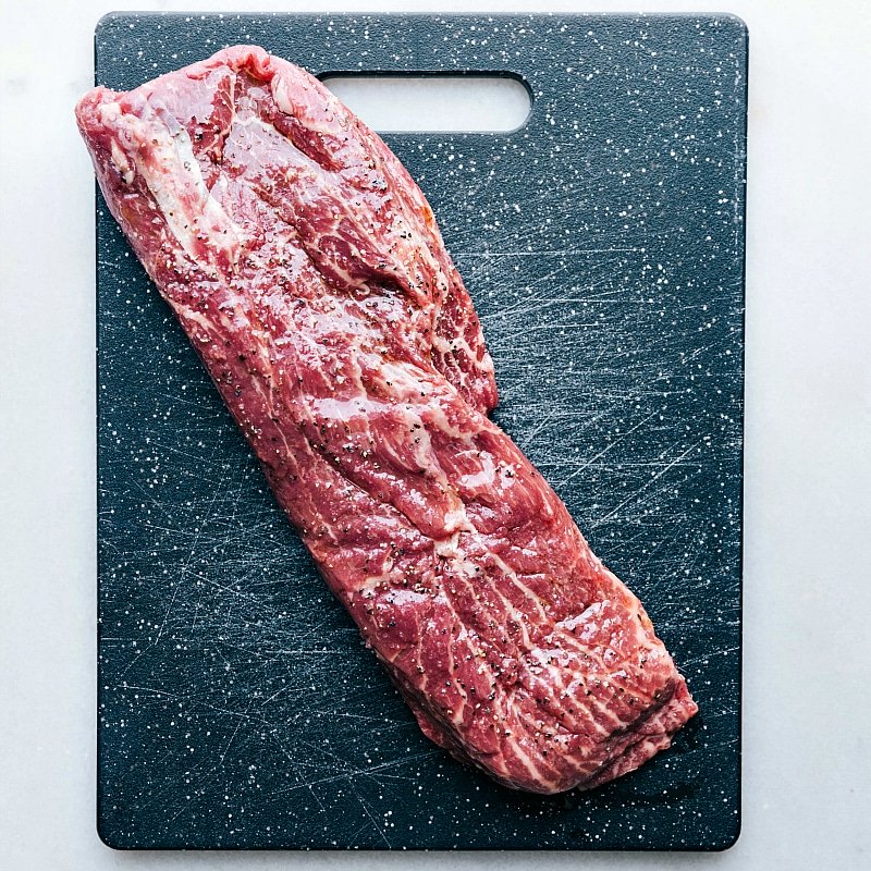 Seasoning Raw Meat for Grilling Raw meat arranged on a cutting board, prepared to be seasoned and grilled.