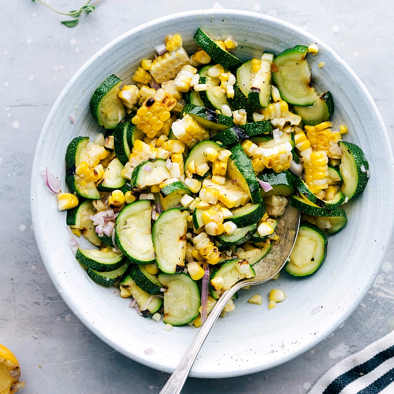 Grilled Corn and Zucchini Salad for Greek Chicken A bowl of grilled corn and zucchini salad, a flavorful side dish accompanying the greek chicken recipe, highlighting the vibrant colors and delicious ingredients.