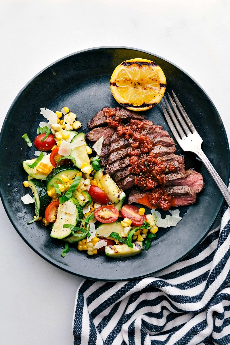 Grilled Flat Iron Steak with Zucchini/Corn Salad A succulent and tender grilled flat iron steak served with a refreshing zucchini and corn salad on the side, promising a delicious and satisfying meal.