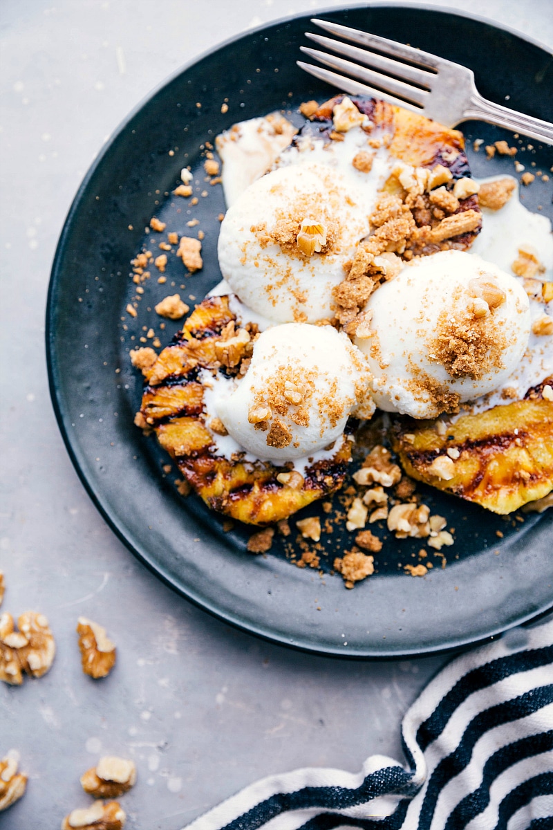 Grilled Pineapple Sundae with Vanilla Ice Cream and Nuts A delightful twist on a classic sundae, featuring grilled pineapple topped with vanilla ice cream and sprinkled nuts, combining warm and cold elements for a unique dessert experience.
