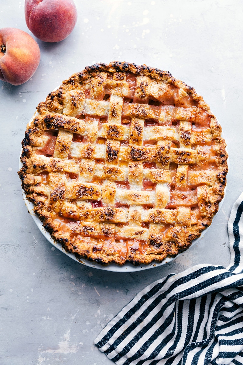 Freshly Baked Peach Pie with Sugar Topping - Accompanied by Fresh Peaches Delicious and sweet peach pie, fresh out of the oven and topped with sugar, accompanied by fresh peaches on the side.