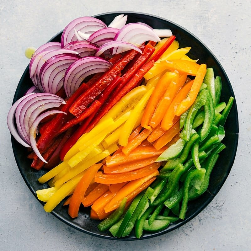 Sliced Veggies for Shrimp Fajitas An assortment of sliced vegetables, including onions and various types of peppers, ready to be used in this recipe.