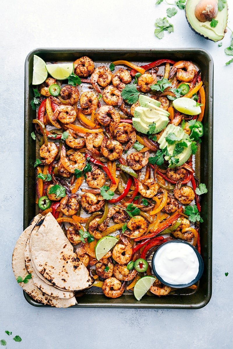 Savory Shrimp Fajitas on Sheet Pan Freshly baked shrimp fajitas on a sheet pan, accompanied by tortillas and a variety of toppings, all set for assembly into a mouthwatering and savory meal.