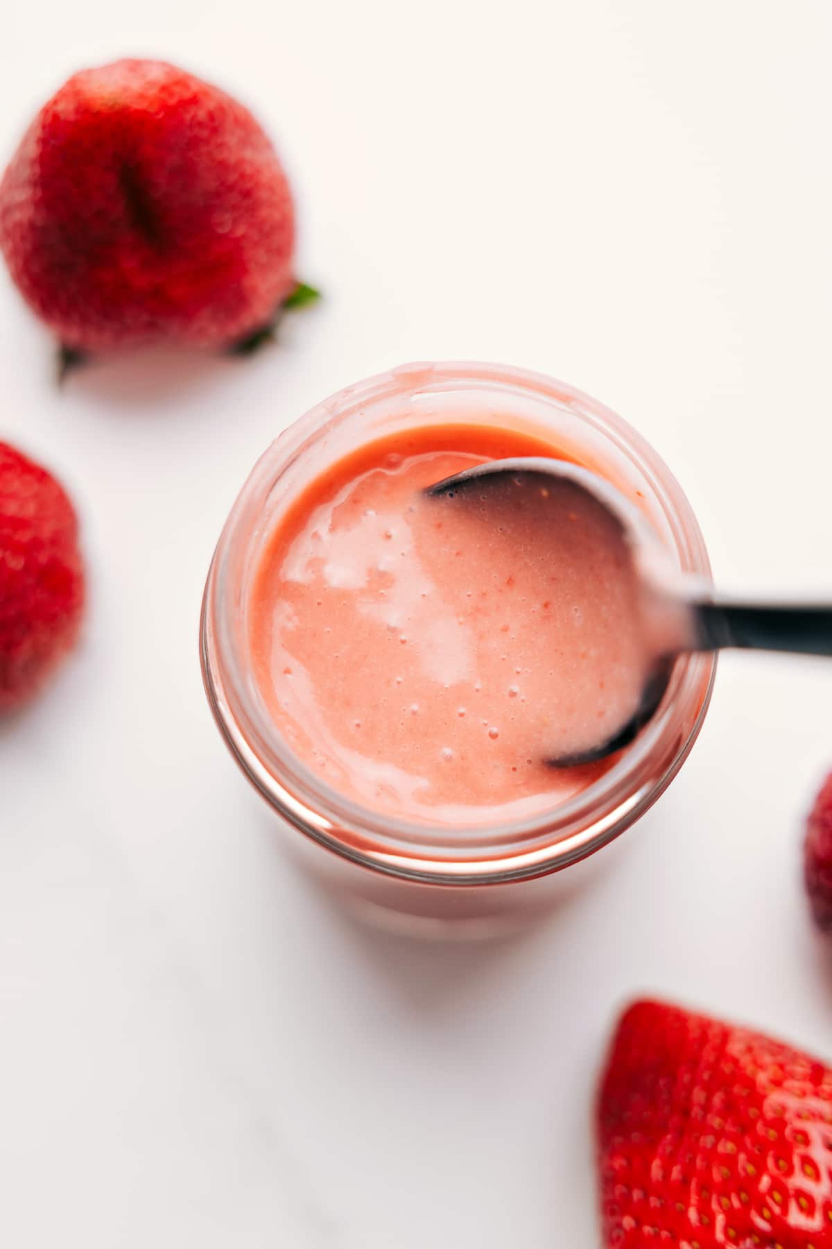Strawberry Vinaigrette in a mason jar with a spoon scooping it up, ready to drizzle and enjoy.