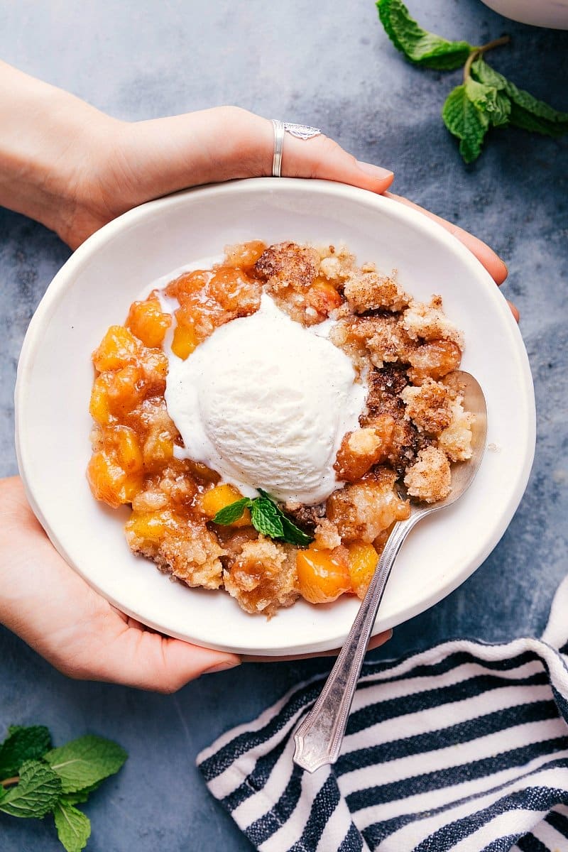 Peach Cobbler with Vanilla Ice Cream - A Sweet Treat Sweet and delicious peach cobbler in a bowl with a scoop of vanilla ice cream on top.