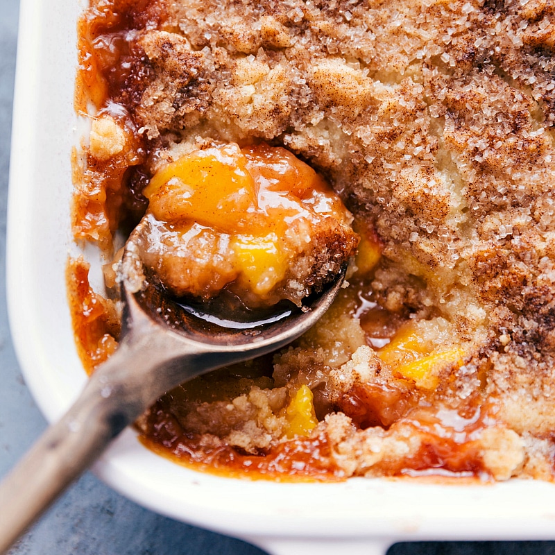 Scooping Peach Cobbler - Revealing the Fruity Interior A spoonful of the dessert being scooped out of the casserole dish, revealing the delicious fruity interior.