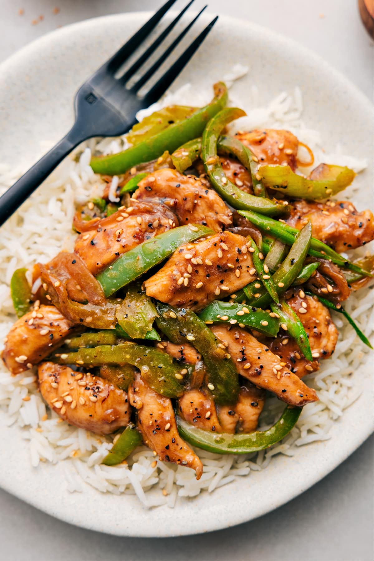 The Best Black Pepper Chicken Recipe Black pepper chicken over a bed of rice and sprinkled with sesame seeds.