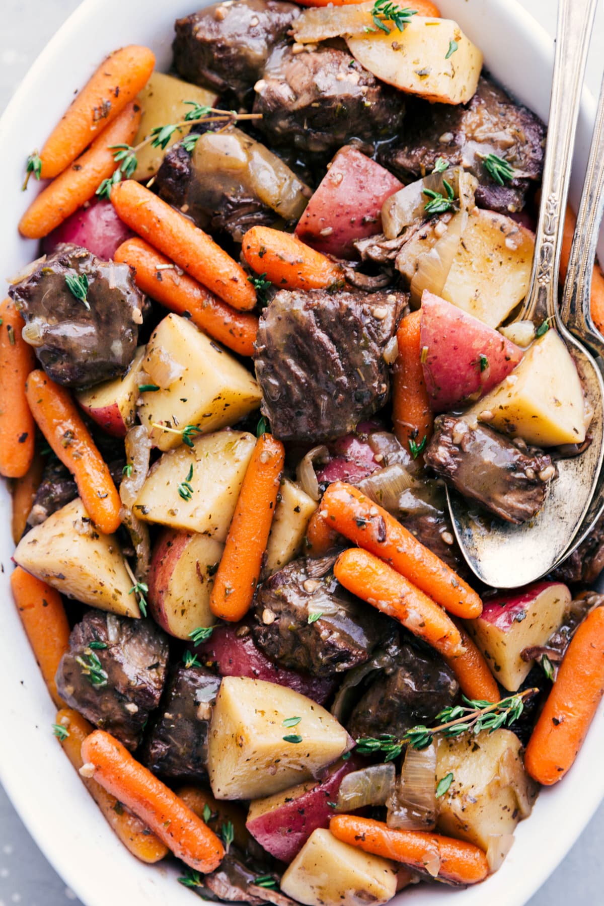 Crockpot roast recipe in a serving dish fresh out of the slow cooker topped with herbs and ready to enjoy.