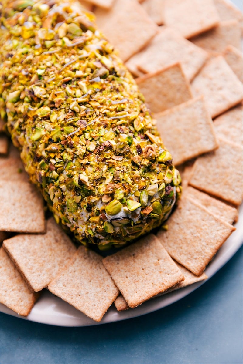 This Pistachio Goat Cheese Ball is one for the books! Tangy goat cheese paired with sweet dried fruit, fresh herbs, and encased in salty pistachios -- your next party needs this appetizer! Recipe via ChelseasMessyApron #appetizer #gameday #snack #best #quick #easy #crackers #familyfriendly #pistachio #goatcheese #ball Image of the Pistachio Goat Cheese Ball ready to be served