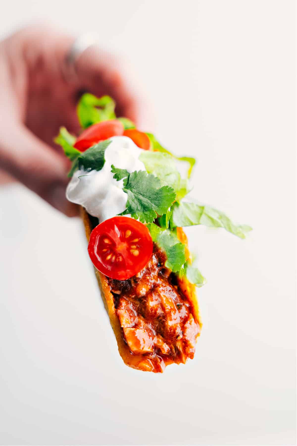 Quick 30-Minute Dinner: Rotisserie Chicken Tacos Rotisserie chicken tacos are held up, topped with sour cream, tomatoes, and cilantro.