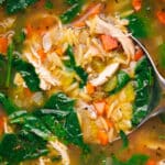 Steaming pot of homemade lemon chicken orzo soup with a ladle inside.