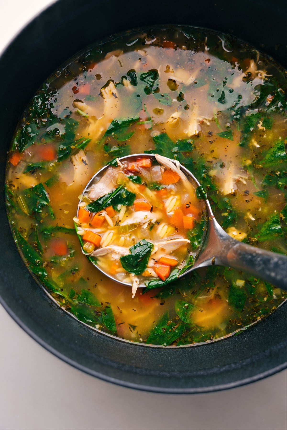 Serving Steaming Lemon Chicken Orzo Soup, Rich in Ingredients Steaming lemon chicken orzo soup in a pot, with a ladle serving a portion rich with ingredients.