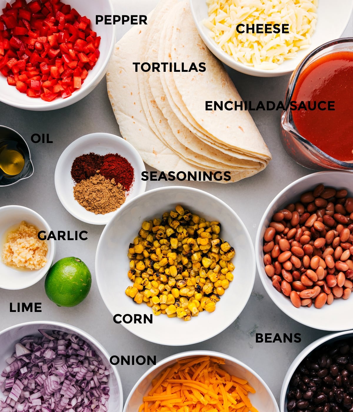 Ingredients In Vegetarian Enchiladas All the ingredients prepped for easy assembly, including veggies, tortillas, sauce, corn, cheese, seasonings, and beans.