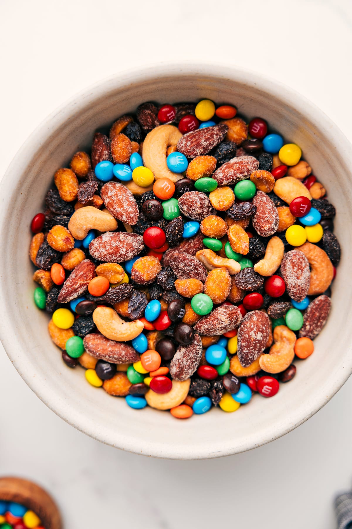 Trail Mix Recipe in a bowl filled with nuts, pretzels, chocolate candies, and dried fruit ready to be enjoyed.