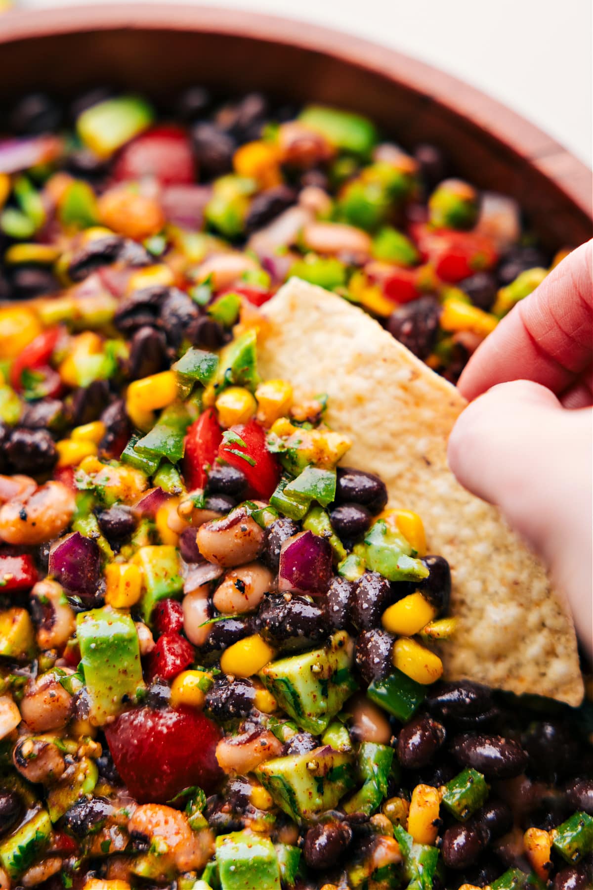 Cowboy Caviar in a bowl with a chip dipping in.