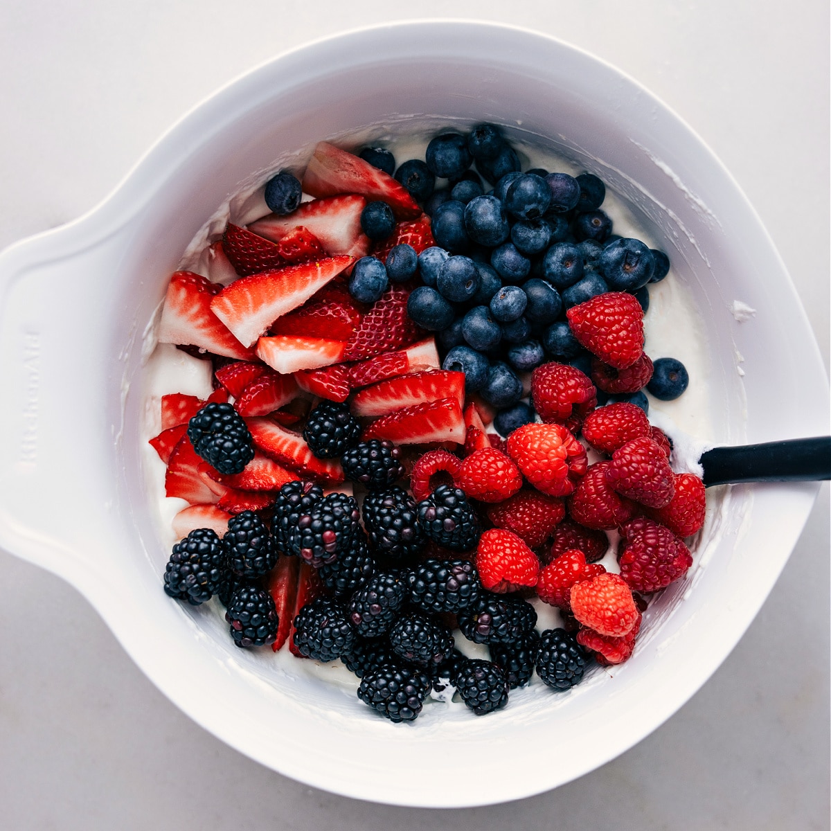 Fold Berries Into The Cheesecake Cream The berries being mixed into the creamy dressing layer.