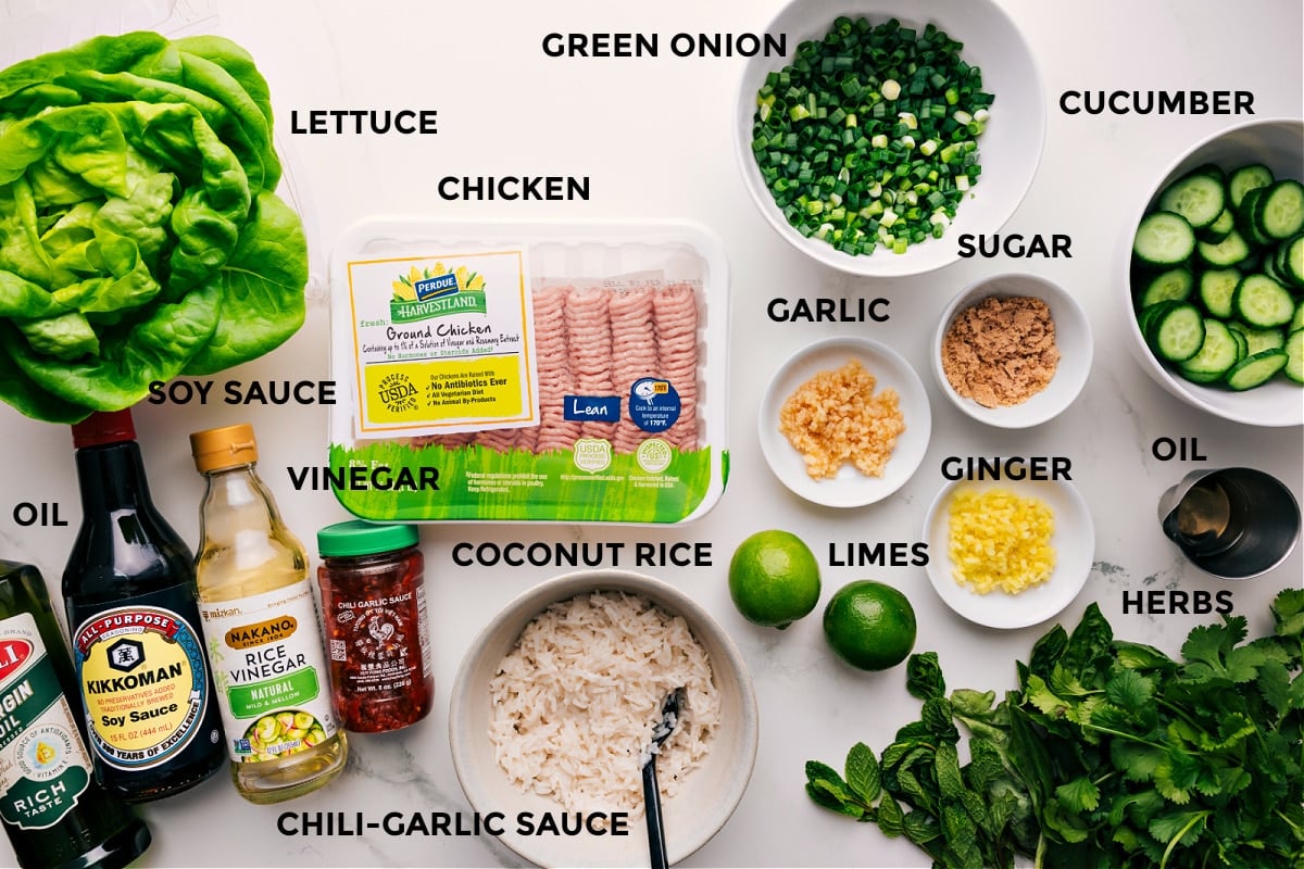 Ingredients In Chicken Larb Recipe All the ingredients in this recipe prepped out for easy assembly including the lettuce, oil, soy sauce, vinegar, chili-garlic sauce, coconut rice, chicken, green onions, limes, garlic, ginger, sugar, cucumbers, and additional herbs.