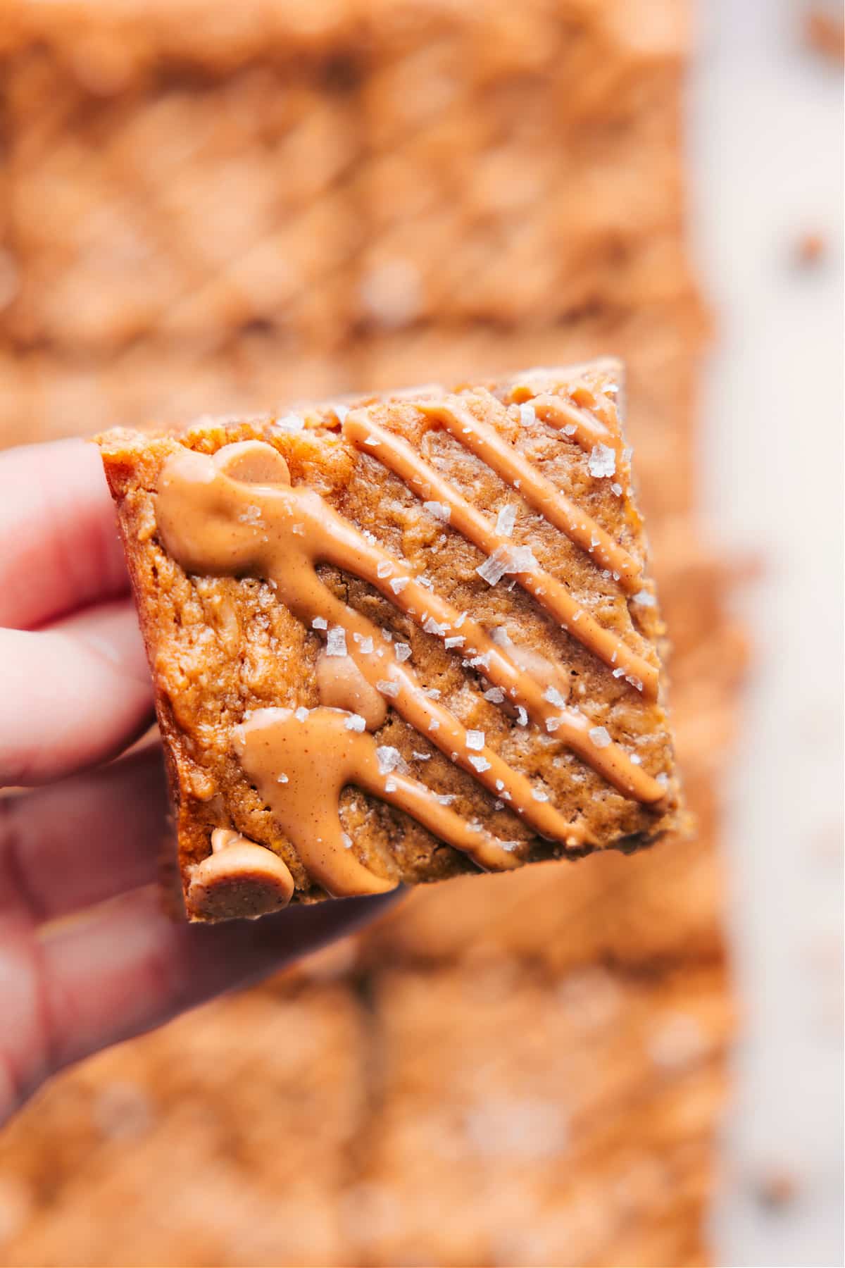 Homemade oatmeal bars recipe topped with peanut butter drizzle and flaky sea salt.