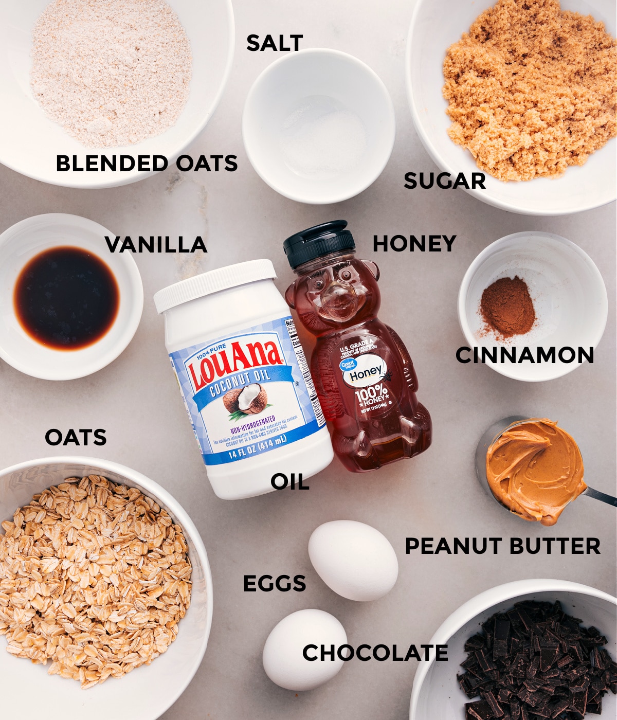 Ingredients For Oatmeal Breakfast Bars All the ingredients prepped for easy assemblyโsugar, oats, honey, cinnamon, eggs, peanut butter, oil, vanilla, and chocolate.