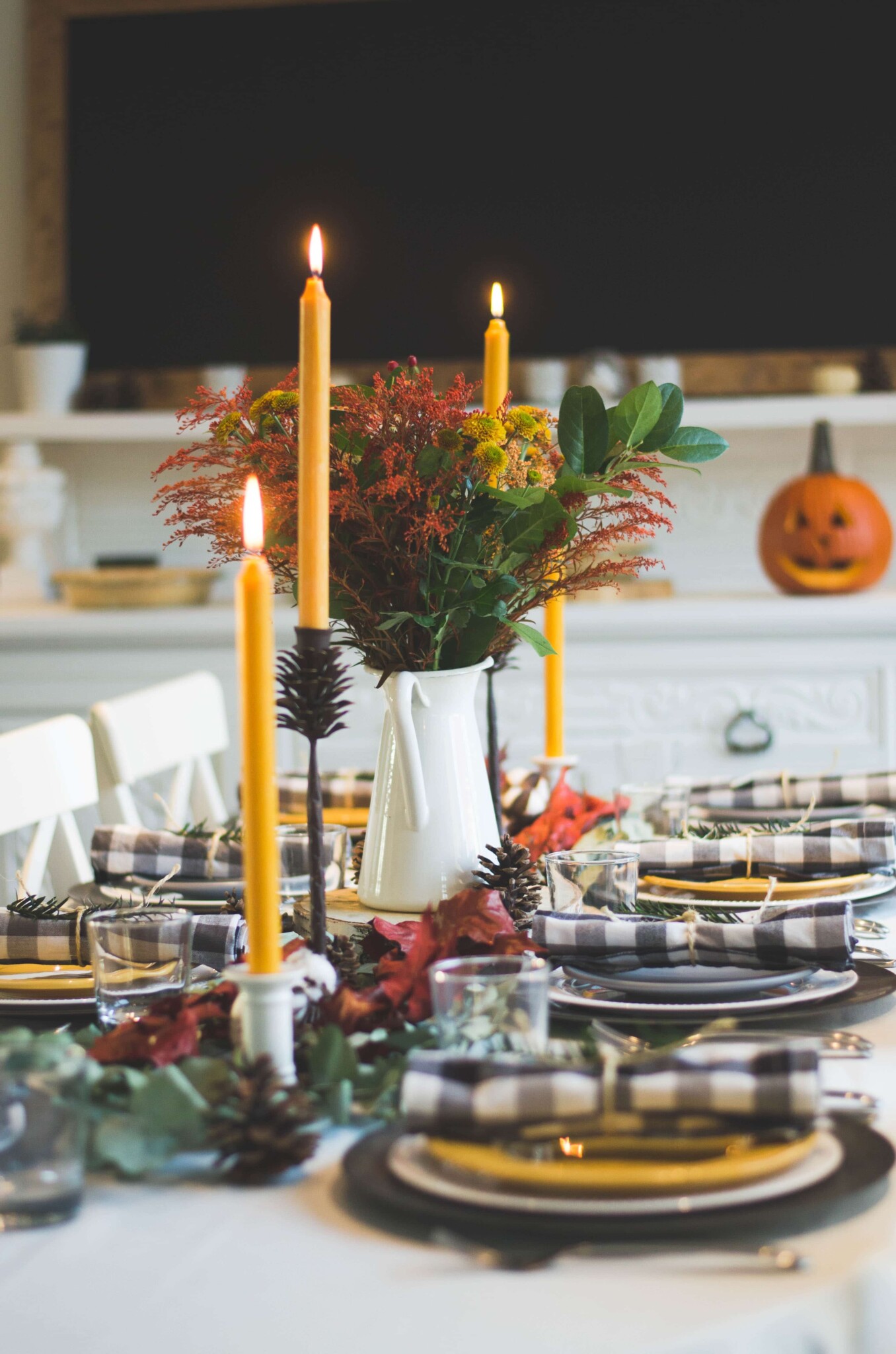 Thanksgiving Table Set with Festive Plates and Candles A Thanksgiving tablescape with plates, napkins, candles and seasonal flowers. Setting the table is an important part of our Thanksgiving planning guide.