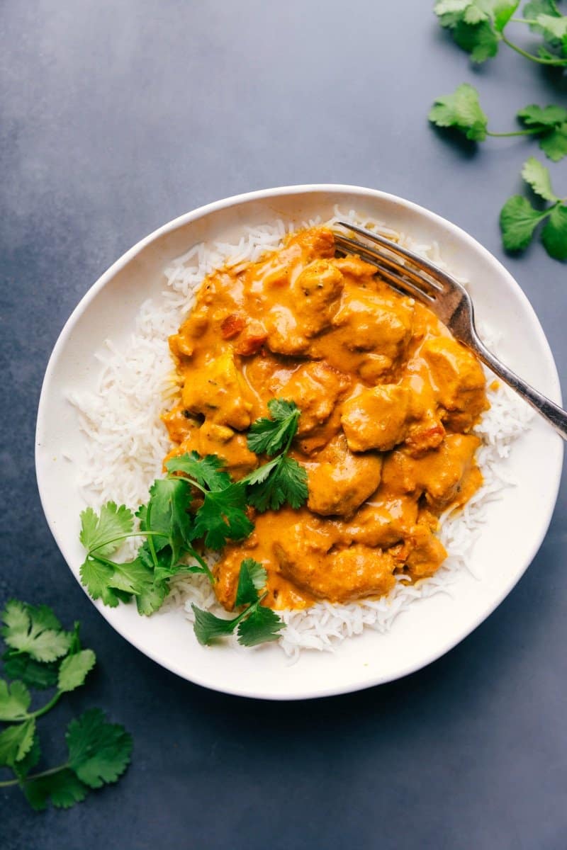 Rich Butter Chicken on a Fluffy Bed of Rice, Topped with Cilantro and Ready to Savor. Plate of butter chicken served on rice, garnished with fresh cilantro.