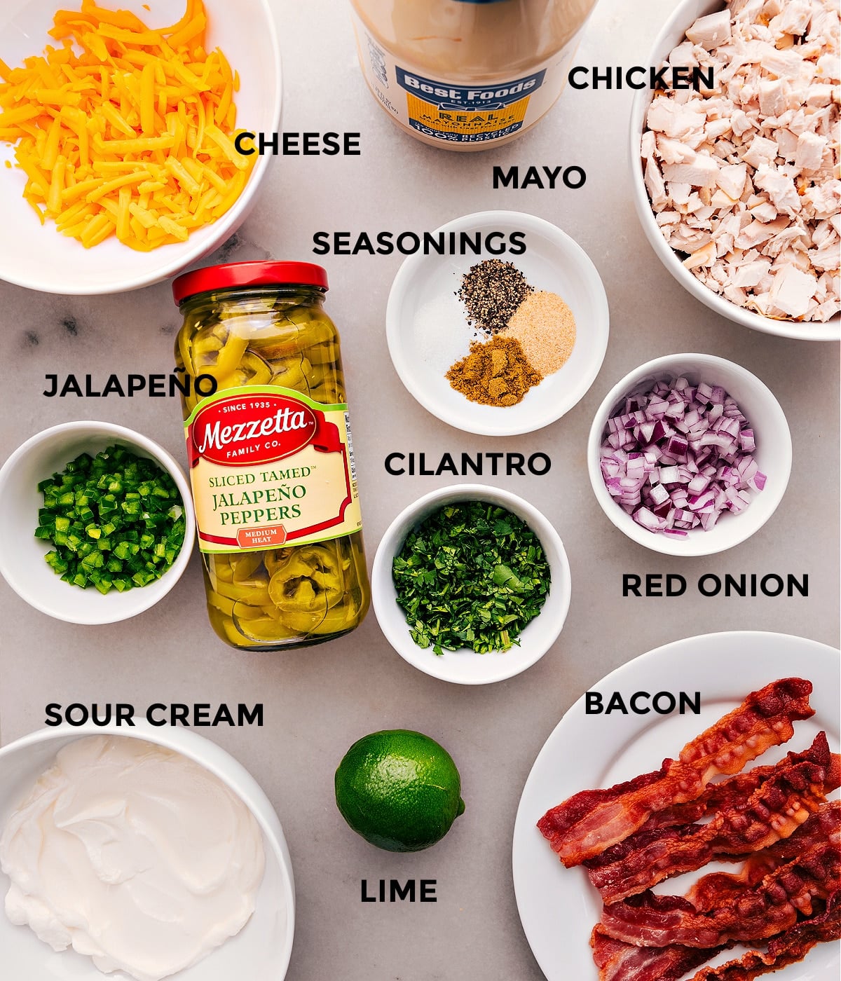 Ingredients In Jalapeño Popper Chicken Salad All the ingredients for this recipe are prepped for easy assembly, including cheese, mayo, eggs, seasonings, meat, and sour cream.