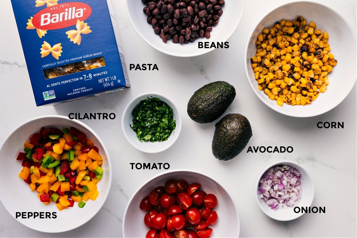 Ingredients In Mexican Pasta Salad All the ingredients prepped for easy assemblyโbeans, pasta, corn, avocado, onion, tomato, cilantro, and peppers.