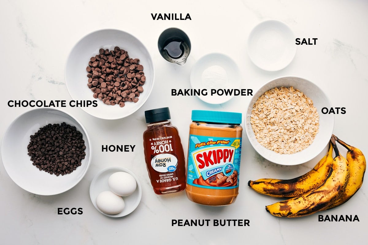 Ingredients In Peanut Butter Banana Muffins with Chocolate Chip Topping All the ingredients in this recipe prepped out for easy assembly including the chocolate chips, eggs, honey, peanut butter, bananas, oats, baking powder, salt, and vanilla.