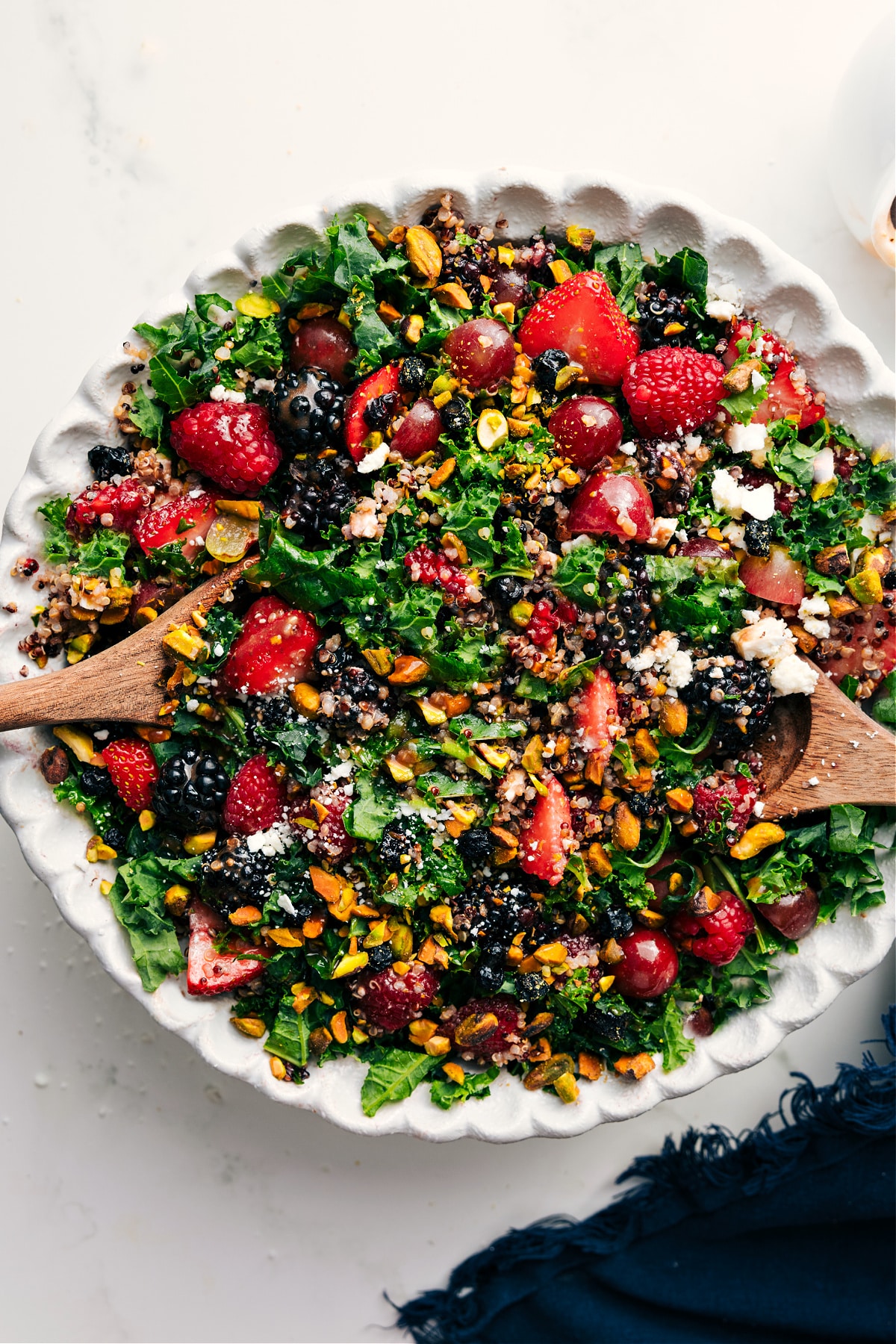Kale Quinoa Salad in a bowl with all the fresh mixings like berries, pistachios, and feta.