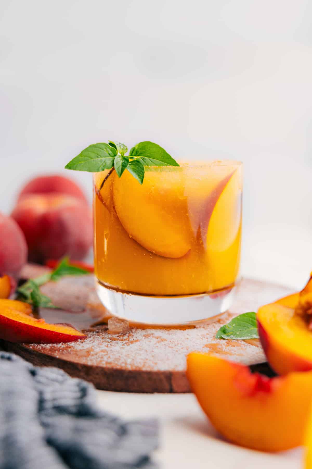 Peach lemonade in a clear glass topped with fresh peach slices and mint leaves.