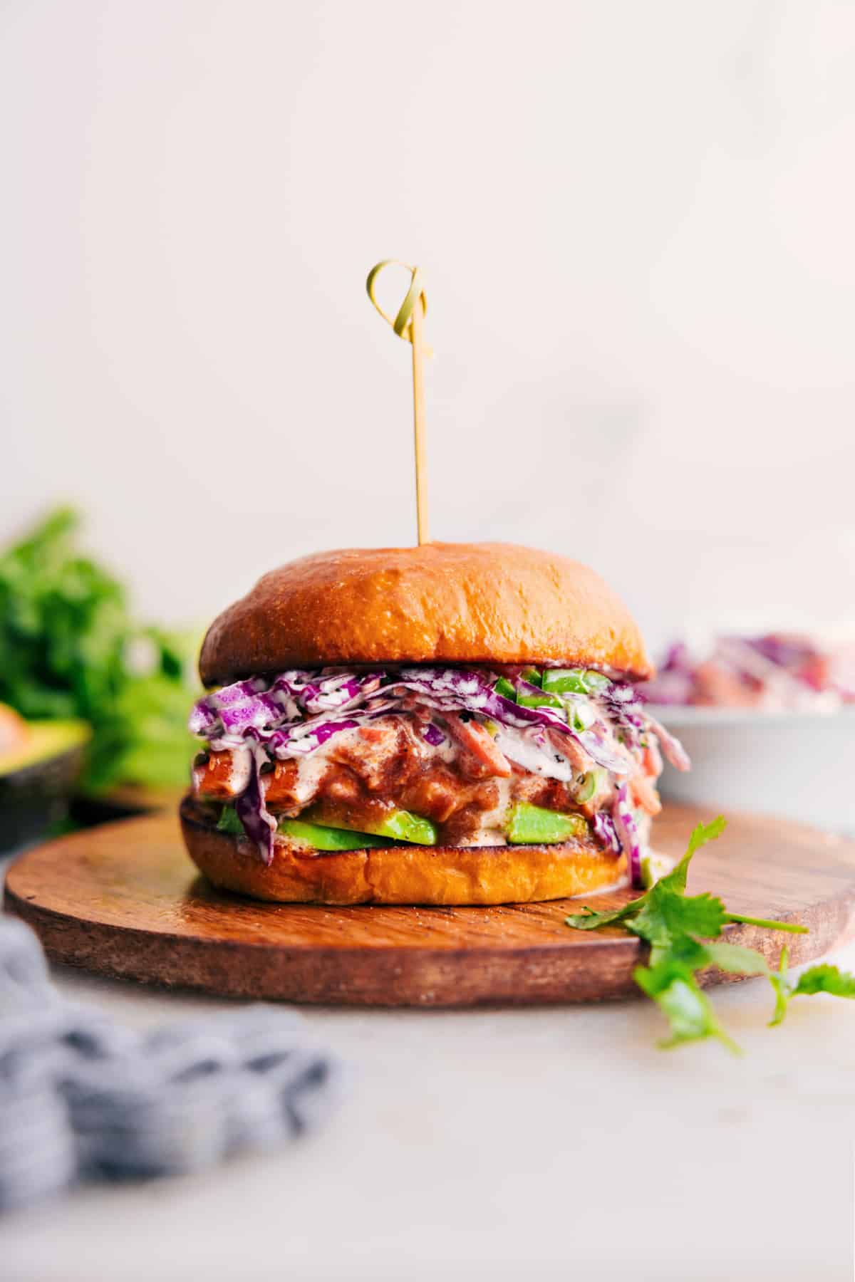 Flavorful And Filling BBQ Chicken Sandwich with Coleslaw on a Bun, Ready to Serve Crockpot BBQ Chicken on a bun, topped with slaw and avocado.