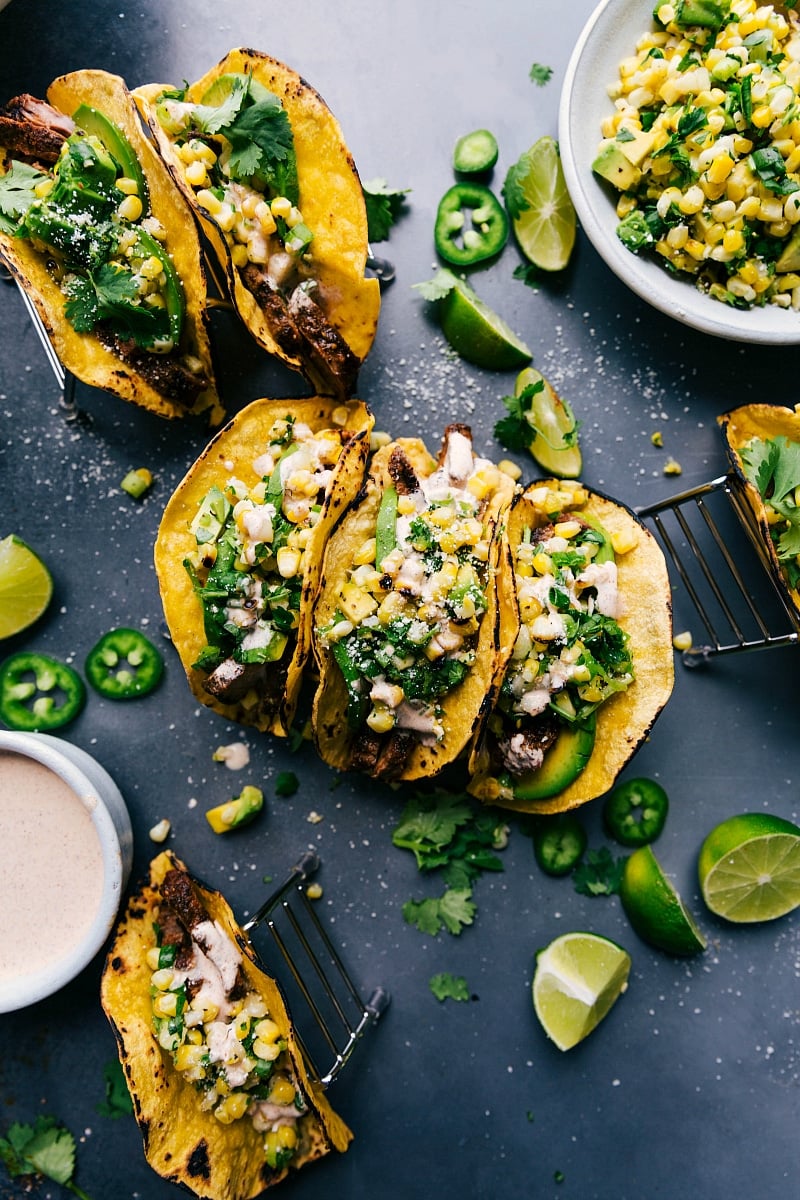 Ready-to-Enjoy Assembled Steak Tacos with Corn Salsa and Cheese Delicious steak tacos garnished with corn salsa, cheese, and various toppings, prepared and served.