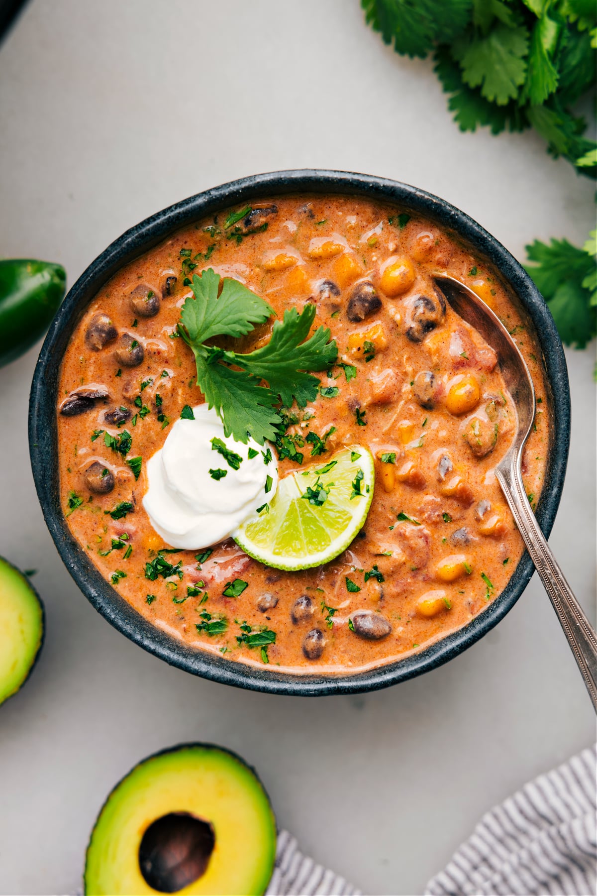 Easy Dump And Go Chicken Crockpot Chili Recipe A big bowl of chicken chili topped with fresh lime, cilantro, and a dollop of sour cream.