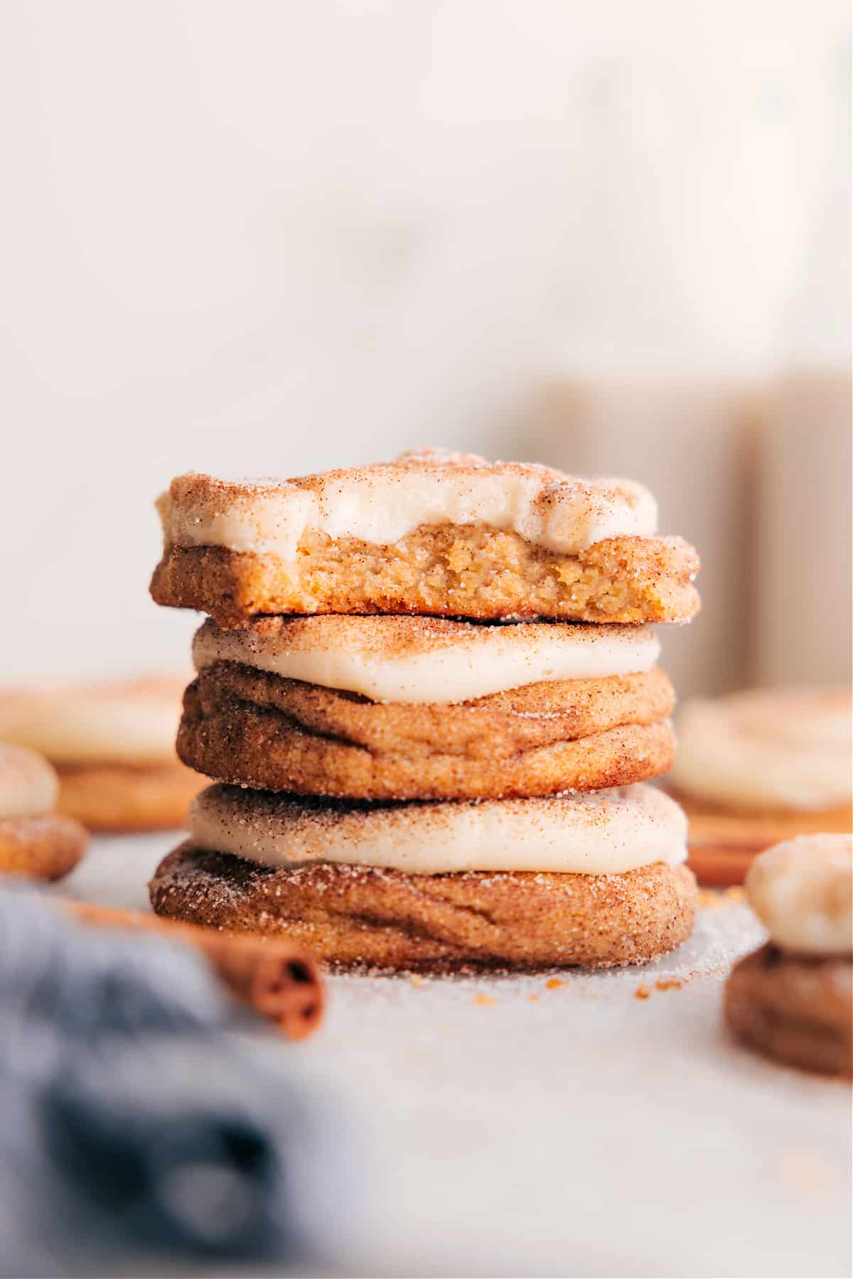 Stacked Cinnamon Roll Cookies on a plate, topped with cream cheese frosting.