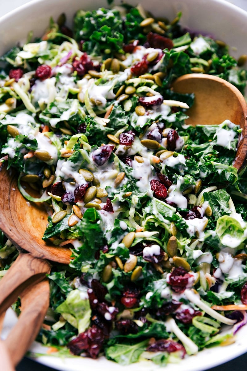 This Kale Salad is loaded with great ingredients -- broccoli slaw, kale, brussels sprouts, dried cranberries, and pepitas. The incredible lemon poppy seed dressing whips together in just a few minutes. This kale salad is nutritious and crunchy with sweet pops of flavor from the dried cranberries and citrus-y dressing. Recipe via chelseasmessyapron #recipes #dressing #massaged #chopped #best #healthy #quick #delicious #side #kale #salad Costco Kale Salad in a bowl ready to be served