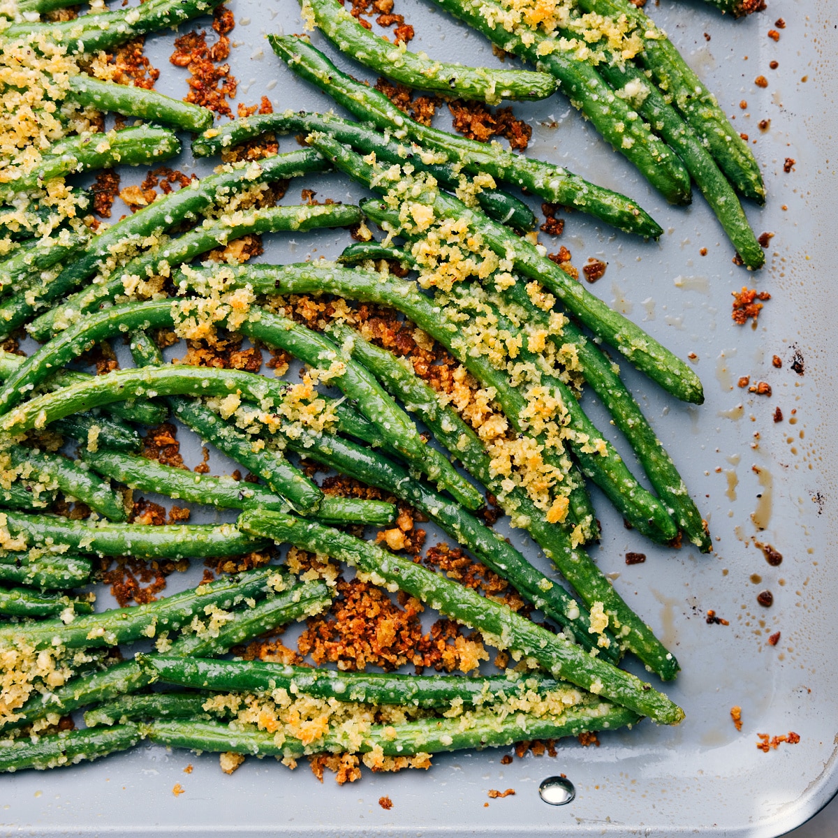 Easy And Delicious Roasted Green Beans Made Two Different Ways Veggies roasting on a tray, turning crispy and delicious.
