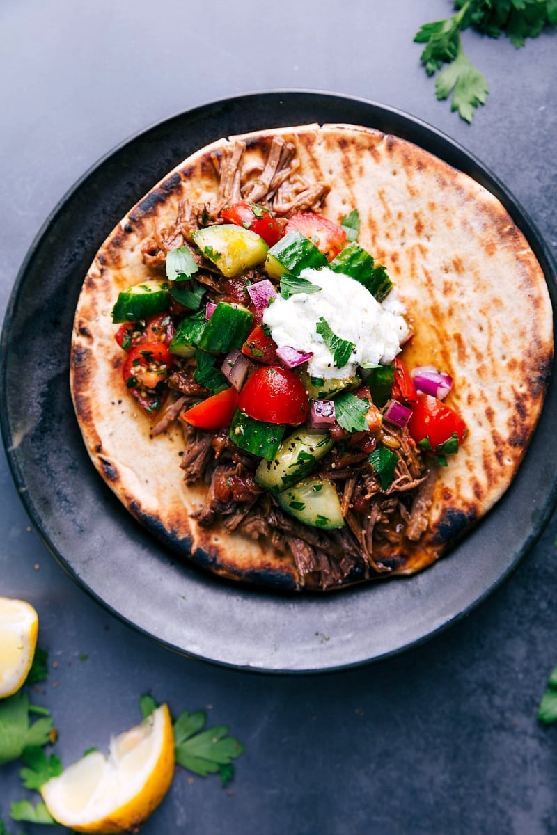Shredded Beef Gyros Shredded beef gyros tucked into warm pita and topped with cucumber tomato salad and creamy tzatziki sauce.