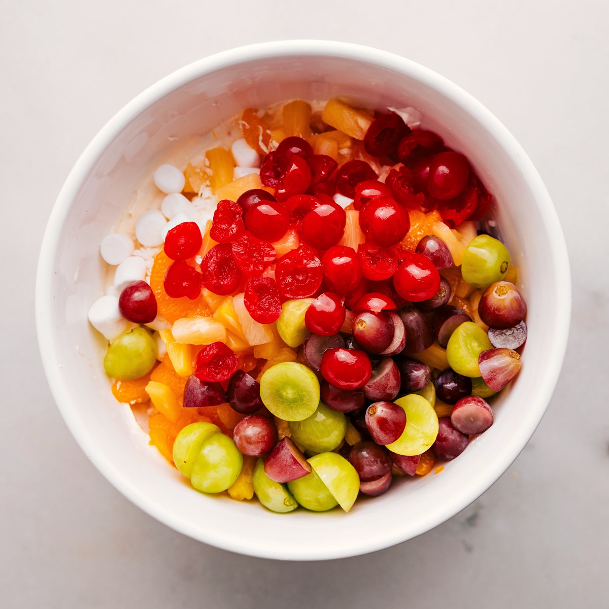 How To Make Ambrosia Salad Recipe All the fruit and marshmallow ingredients added to a bowl.