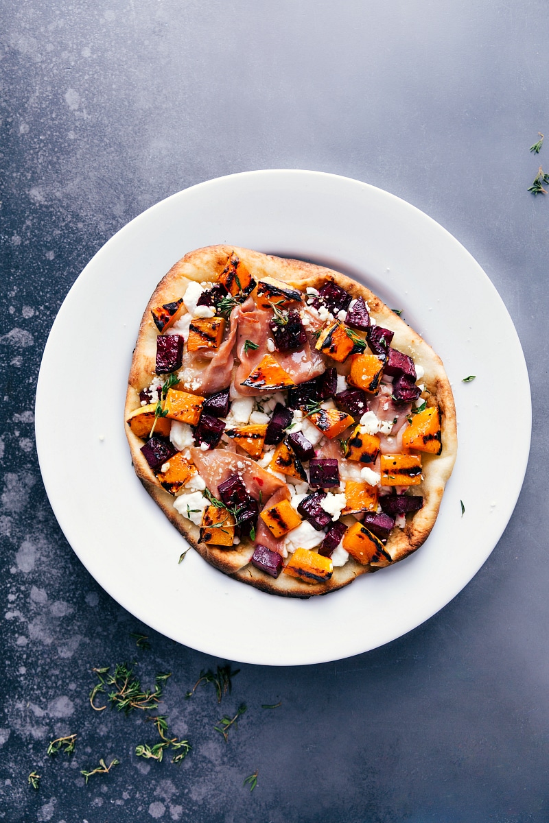 This Beet and Goat Cheese Flatbread makes for a show-stopping, flavorful holiday appetizer. These flatbreads are cooked on the grill (save that precious oven space!) and are topped with grilled butternut squash and beets using Home Depotโs Weberยฎ E-Spirit Black grill! Recipe via chelseasmessyapron #pizza #healthy #quick #easy #simple #fall #grilled #dinner #butternutsquash #thyme #beet #goatcheese #flatbread Overhead image of the beet and goat cheese flatbread fresh off the grill